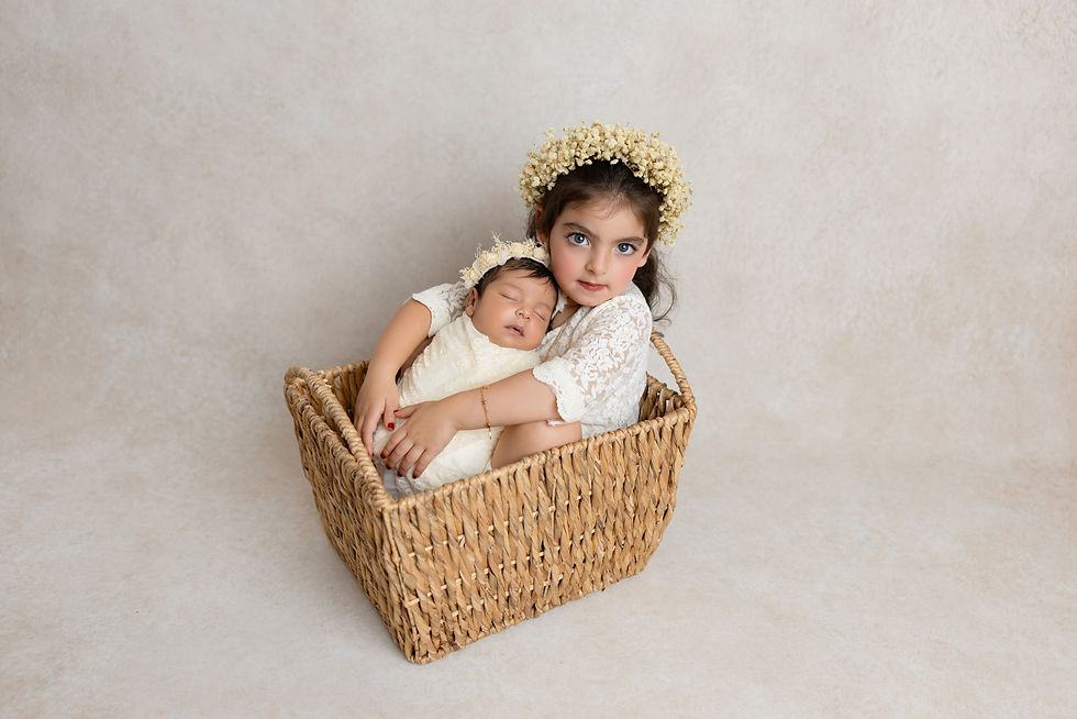 Big sister holding newborn baby in wicker basket – family newborn session in San Diego.