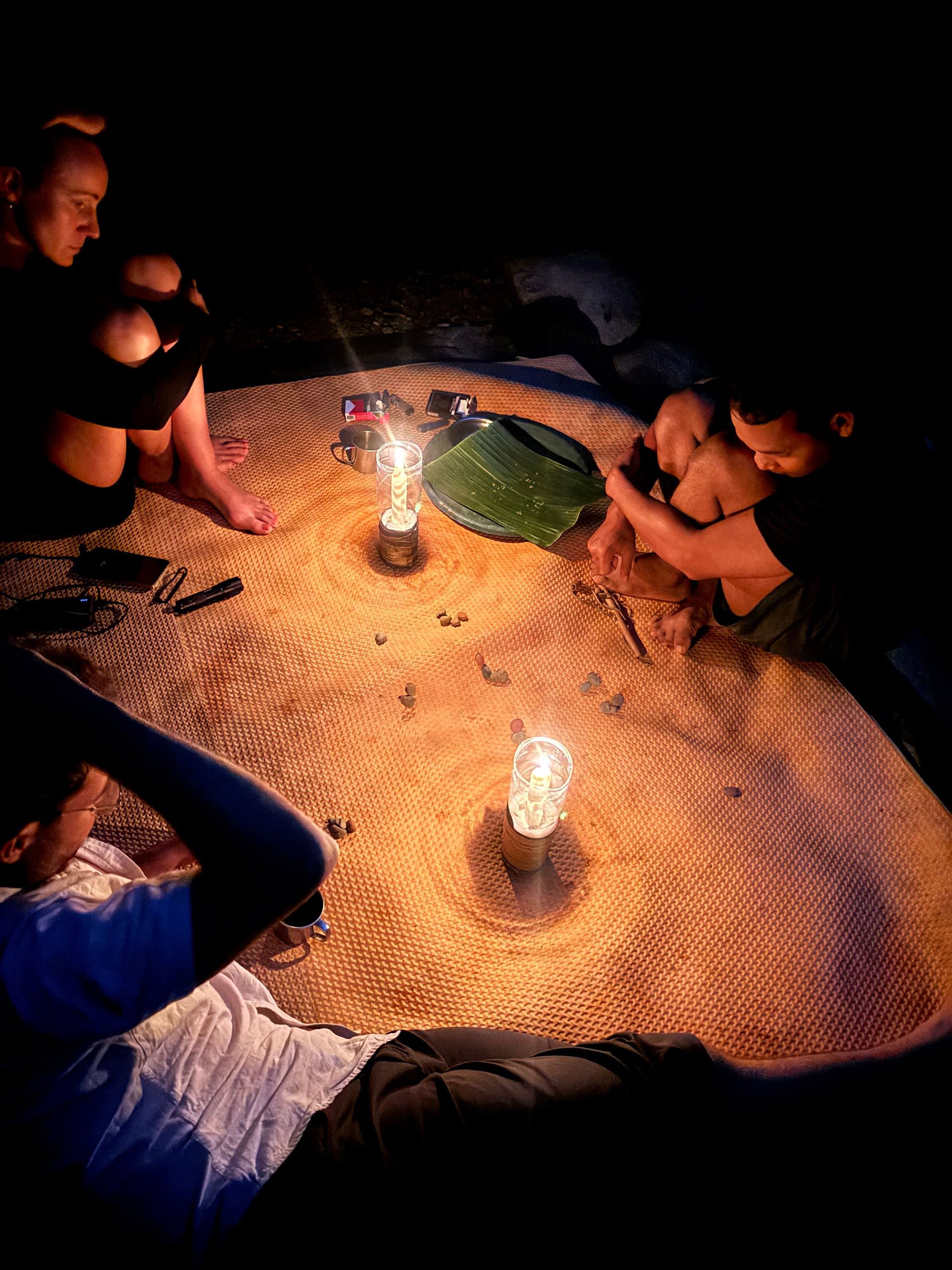 People sitting on a mat near candles.