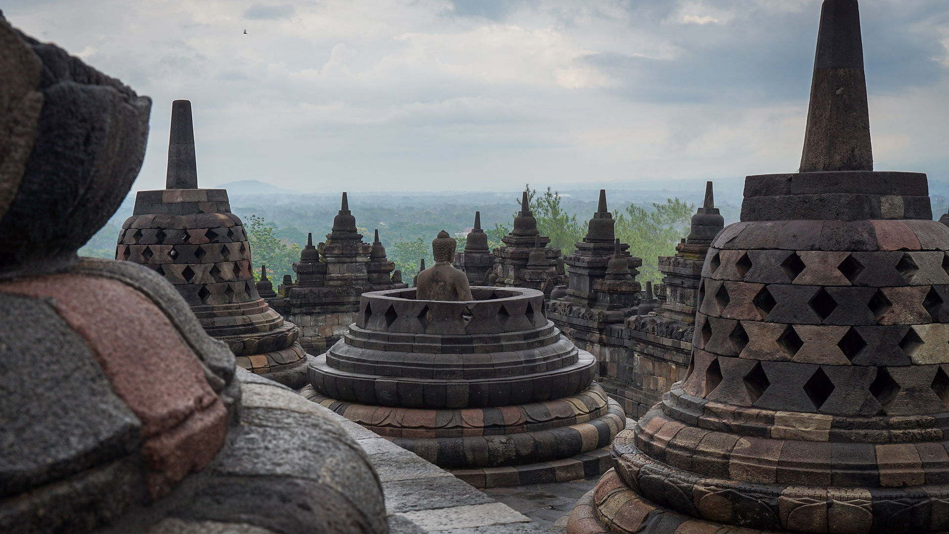 Ancient stupas with a buddha overlooking a lush valley.