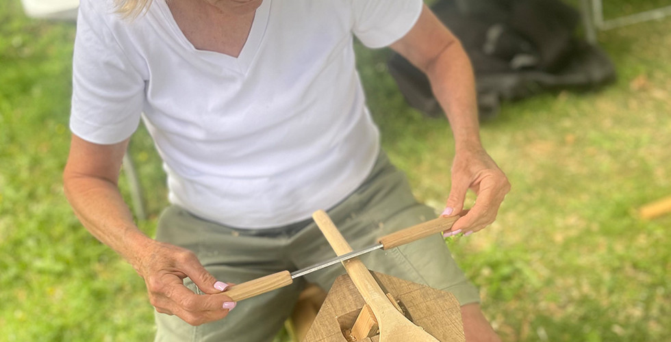 Student using the draw knife to shape the handle of her spoon