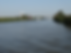 The Norfolk Broads with a few boats sailing down it and an old-fashioned windmill in the background.