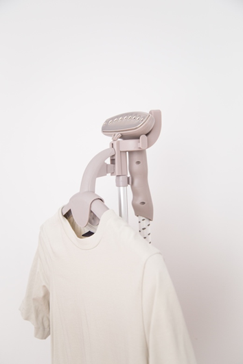 A nude coloured travel steamer with a cream t-shirt hanging on its hanger.