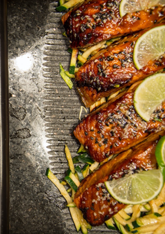 Grilled salmon on a bed of courgette garnished with lime and lemon slices.