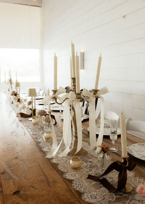 Gold candelabras with cream ribbons on a wedding head table
