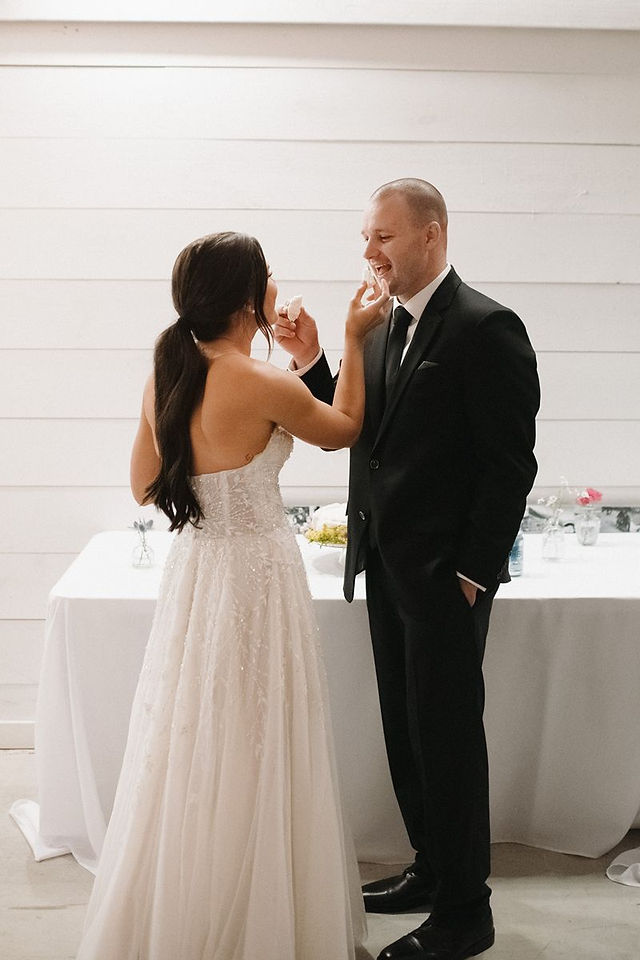 feeding each other cake at white barn wedding venue
