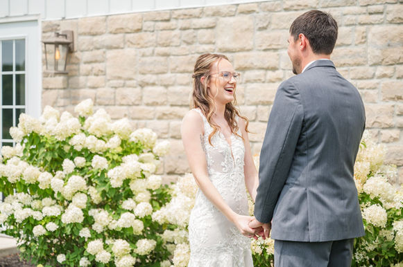 Bride looking at groom next to hydrangeas