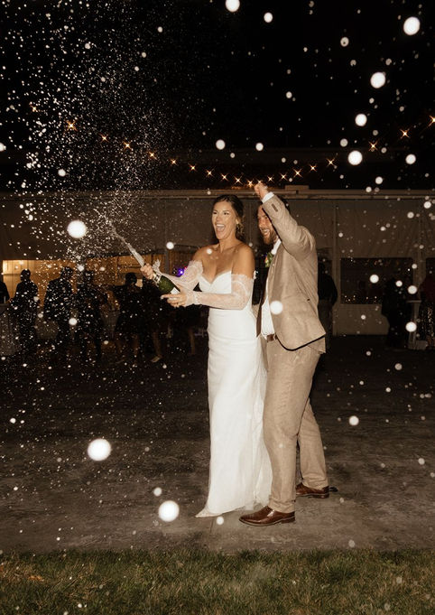 Bride and groom popping champagne