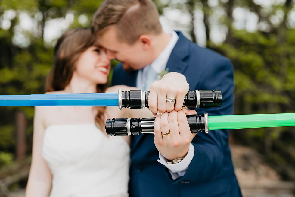 bride and groom holding lightsabers