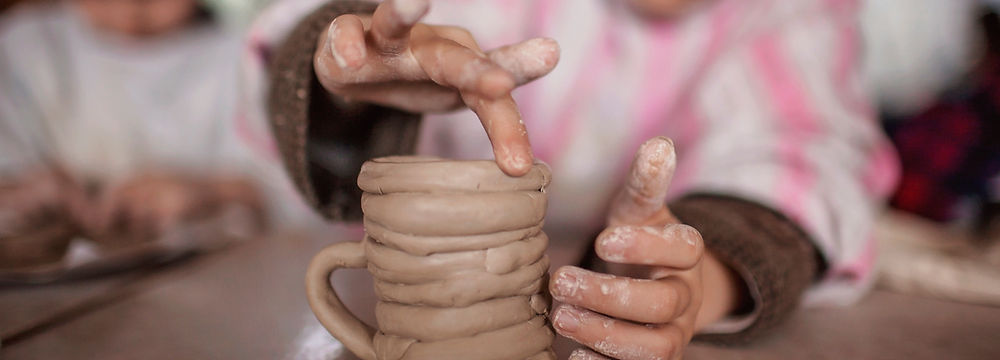 Child making a clay pot