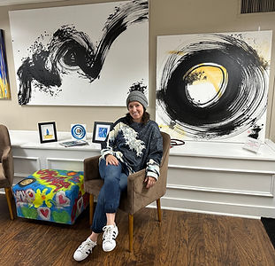 Artist Celeste Seitz sitting in front of artwork showing Enso