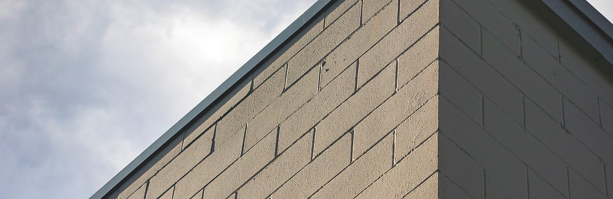 corner of brick wall with clouds behind_