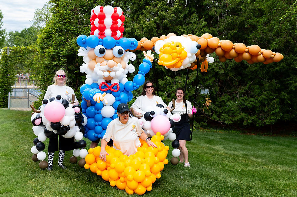 Uncle Sam, the bald eagle, cows, and cheese balloon costumes together on a lawn before the parade.