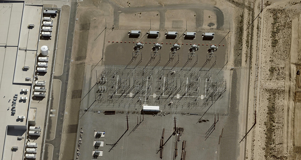 Aerial detail of the dedicated high-voltage substation serving the Los Lunas campus. The installation features a dense array of transmission switchgear, step-down transformers, and bus bar configurations arranged across a gravel-compacted switching yard — infrastructure characteristic of utility-scale power intake at the 230kV–500kV range typical of hyperscale facilities drawing in excess of 100–300 MW of contracted capacity. A row of prefabricated equipment enclosures along the perimeter likely houses protection relays, SCADA control systems, and metering equipment. Transmission line termination structures visible at the lower frame indicate direct interconnection to the regional grid — in this case, the Public Service Company of New Mexico (PNM) transmission network. The substation's footprint and equipment density are consistent with a purpose-built, campus-exclusive power delivery point, bypassing shared distribution infrastructure in favor of dedicated grid access — a configuration that signals both Meta's negotiating leverage with the utility and the scale of power draw the campus requires. Photo taken November 7, 2025. Source: MMCG Invest, LLC / EagleView.