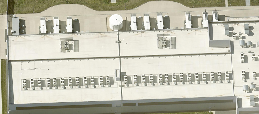 Rooftop cooling comparison, Meta Sarpy County Campus, Springfield, Nebraska. This single frame contains the entire history of hyperscale computing's thermal evolution. The upper half of the image shows the roofline of an older data hall, built for conventional CPU server workloads: widely spaced air-handling units, modest thermal load, generous whitespace between mechanical units. The lower half tells a categorically different story. The dense, unbroken row of multi-fan dry cooler arrays running the full length of the newer hall is the mechanical signature of AI infrastructure — specifically, the dramatically higher heat densities generated by GPU clusters. Where a traditional server rack dissipates 5–10 kilowatts, a rack of NVIDIA H100s generates 40–70 kilowatts; Meta's next-generation Catalina liquid-cooled pods push that to 140 kilowatts per rack. The cooling plant must scale accordingly. The cylindrical white tank at upper center is a thermal buffer vessel — chilled water storage that absorbs load spikes during peak inference demand without requiring the mechanical plant to cycle. The expansion joint running vertically through the center of the frame marks the boundary between two construction phases, separated by perhaps three years in calendar time but an entire technological generation in compute density. No financial disclosure, no earnings call, no analyst report captures this transition as plainly as the roofline does. Photo taken by May 8, 2025, source: MMCG Invest, LLC/EagleView