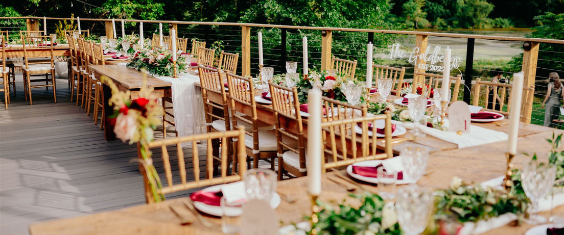 Long dining tables arranged in a u-shape and decorated with tapered candles and garland.