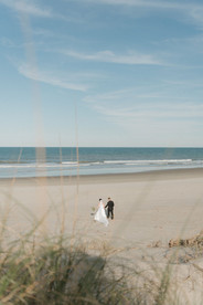 Newlyweds embracing on the sand during sunset portraits in Corolla