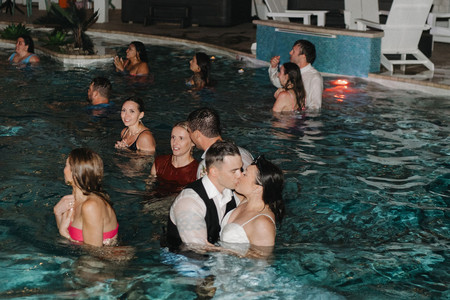 Bride and groom jumping into the pool to end their wedding celebration