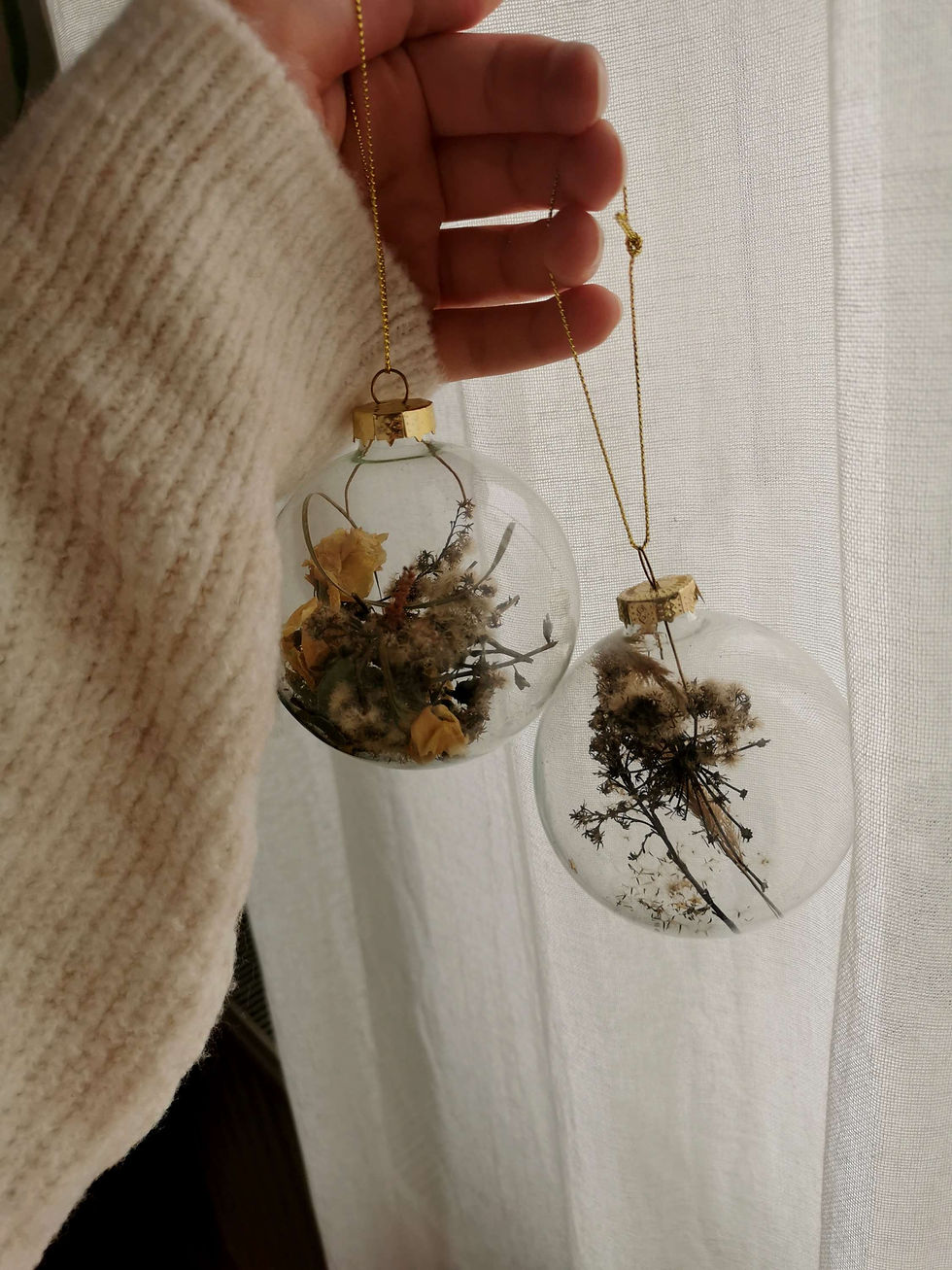 Women hand holding Christmas glass ornaments filled with flowers
