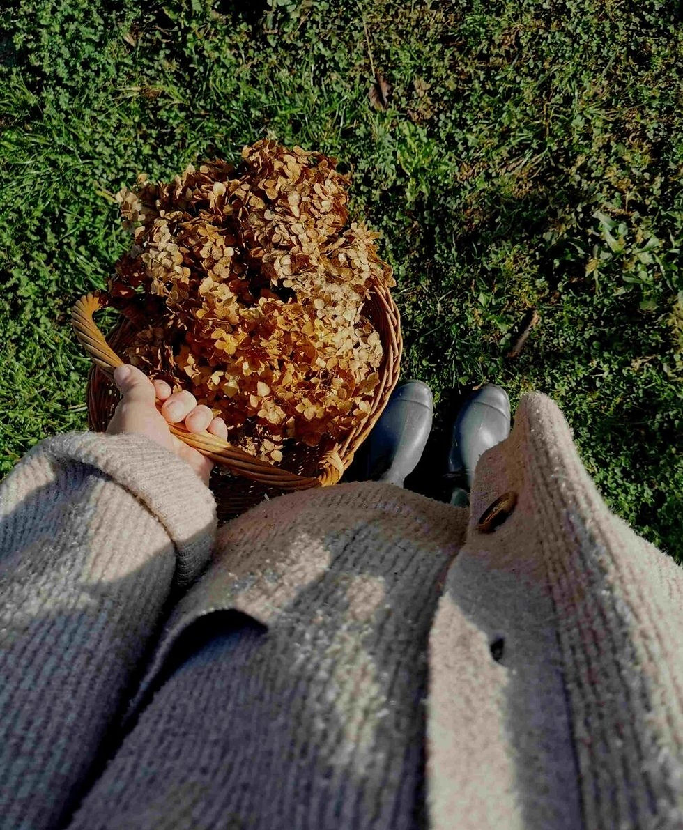 Women holding basket full of autumnal flowers.