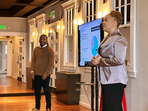 Keith and Christina Blocker stand before the South Sound Business Support Services Ecosystem, presenting research from a collaborative project with the Black Collective and the Washington State Department of Commerce. 