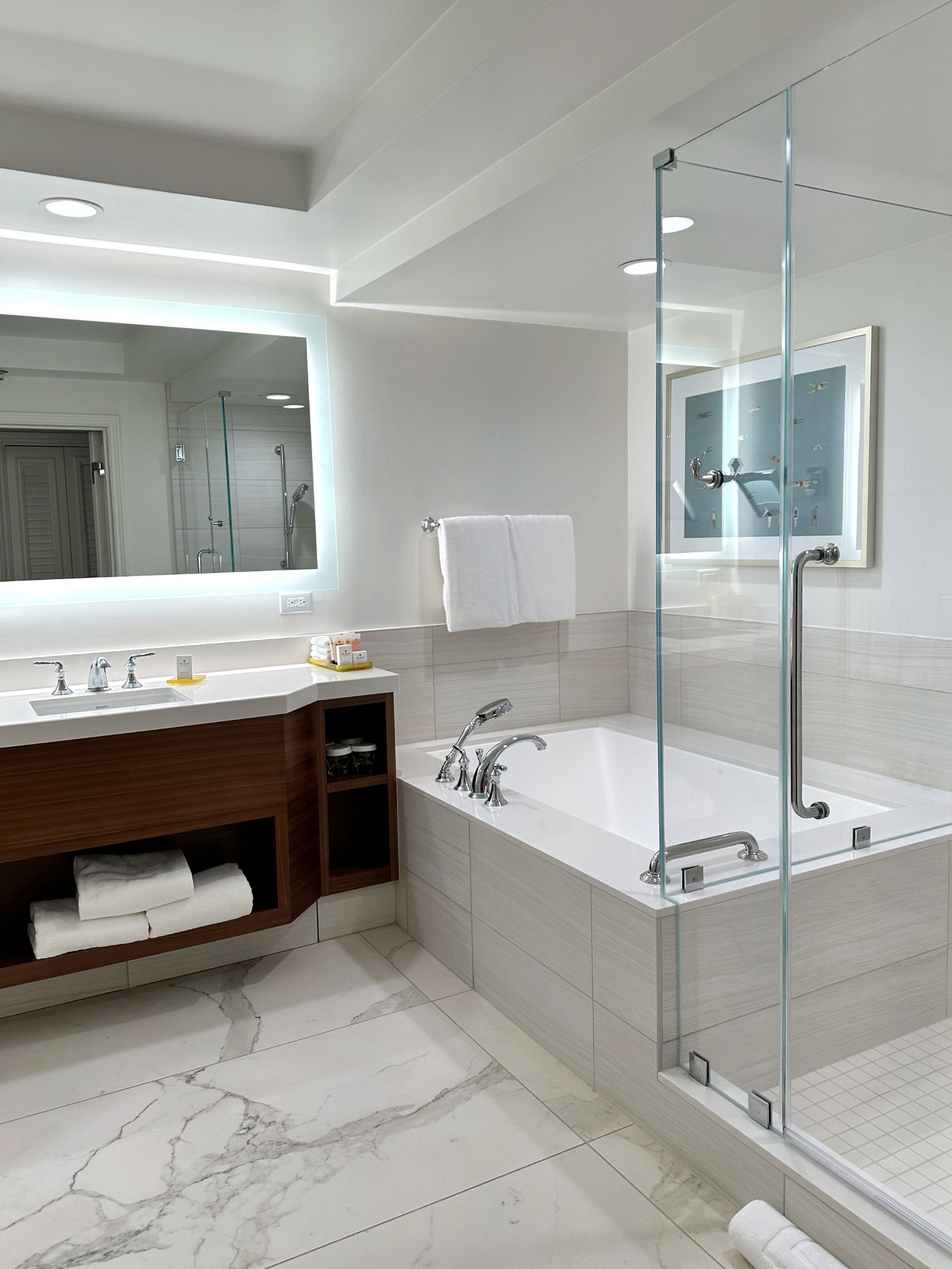 interior of a double ocean view room bathroom at the Grand Wailea, there is a large soaking tub, separate standing shower, lit vanity, and marble accents in the room