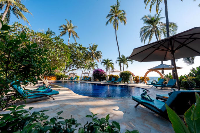 Außenpool des Holiway Garden Resort & Spa auf Bali mit Sonnenliegen, Palmen und tropischer Gartenanlage.
