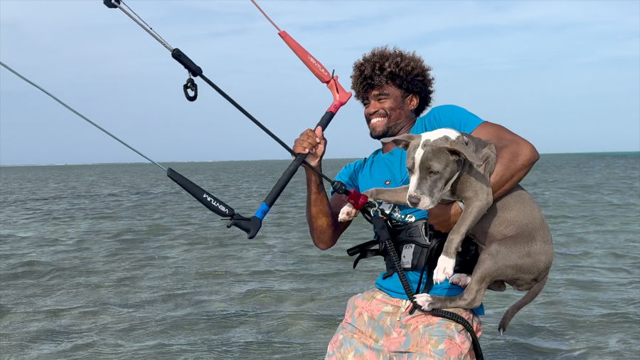 Smiling Davisito kitesurfing while holding Coco Chanel in the ocean