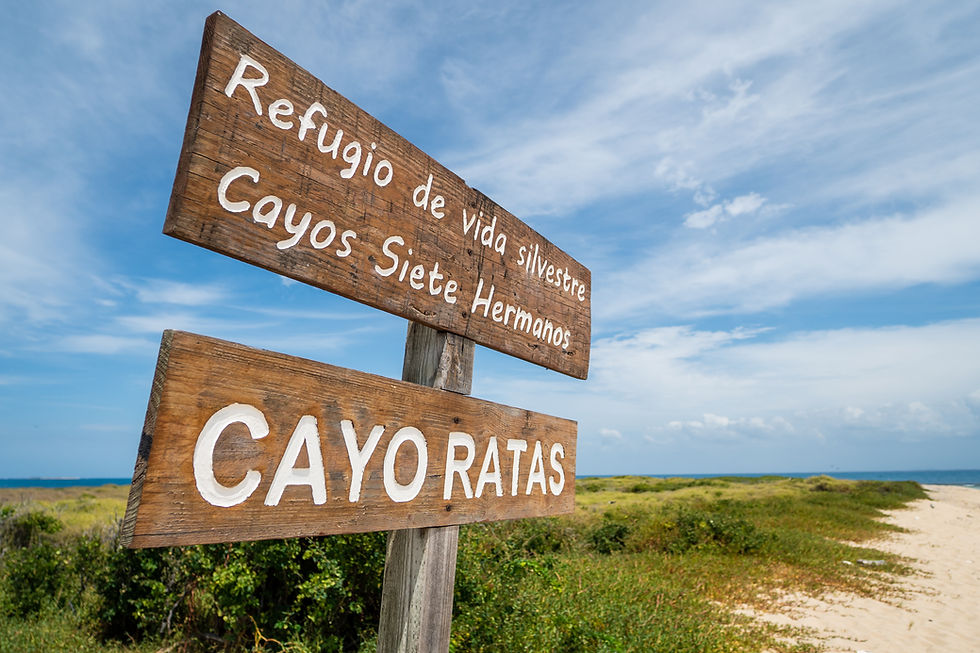 A wooden sign reading “Refugio de Vida Silvestre, Cayos Siete Hermanos, Cayo Ratas” marking the wildlife refuge