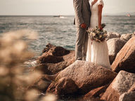 Création d'un moodboard d'un couple de mariés se regardant avec tendresse, debout sur des rochers près de la mer