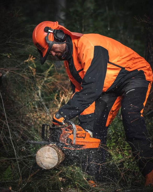 Oranssiin pukeutunut metsuri sahaa moottorisahalla puun runkoa