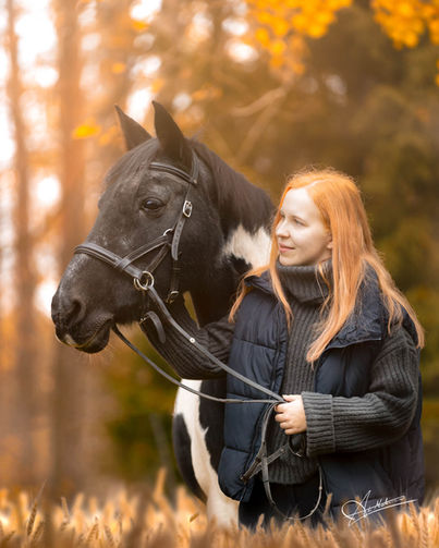 Nainen heinäpellossa hevosensa kanssa