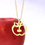 Thumbnail: Gold apple necklace hanging in front of apple. The pendant is flat and shiny, showing the section of apple with seeds.