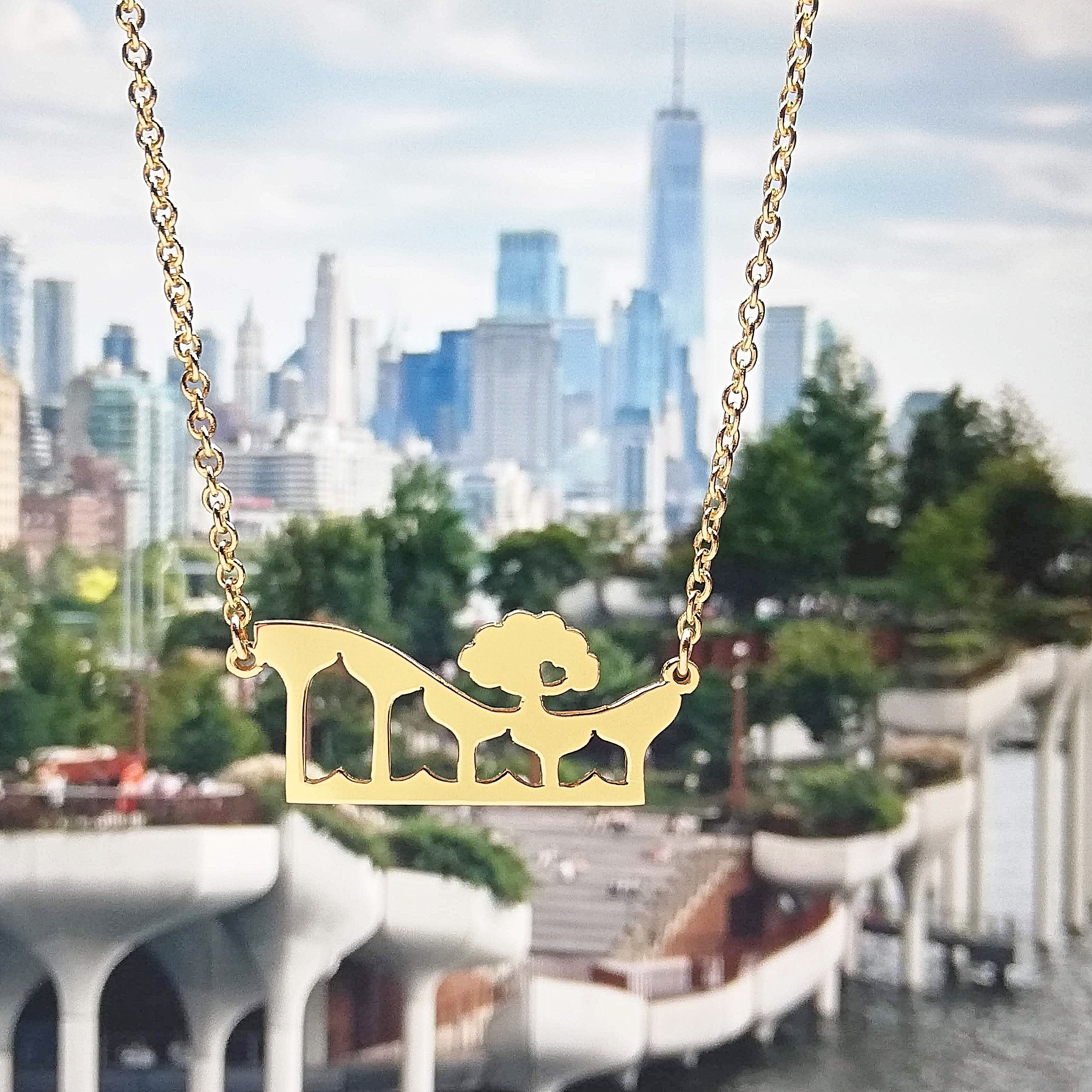 Gold cutout little island shape necklace. The background is Manhattan east side view.