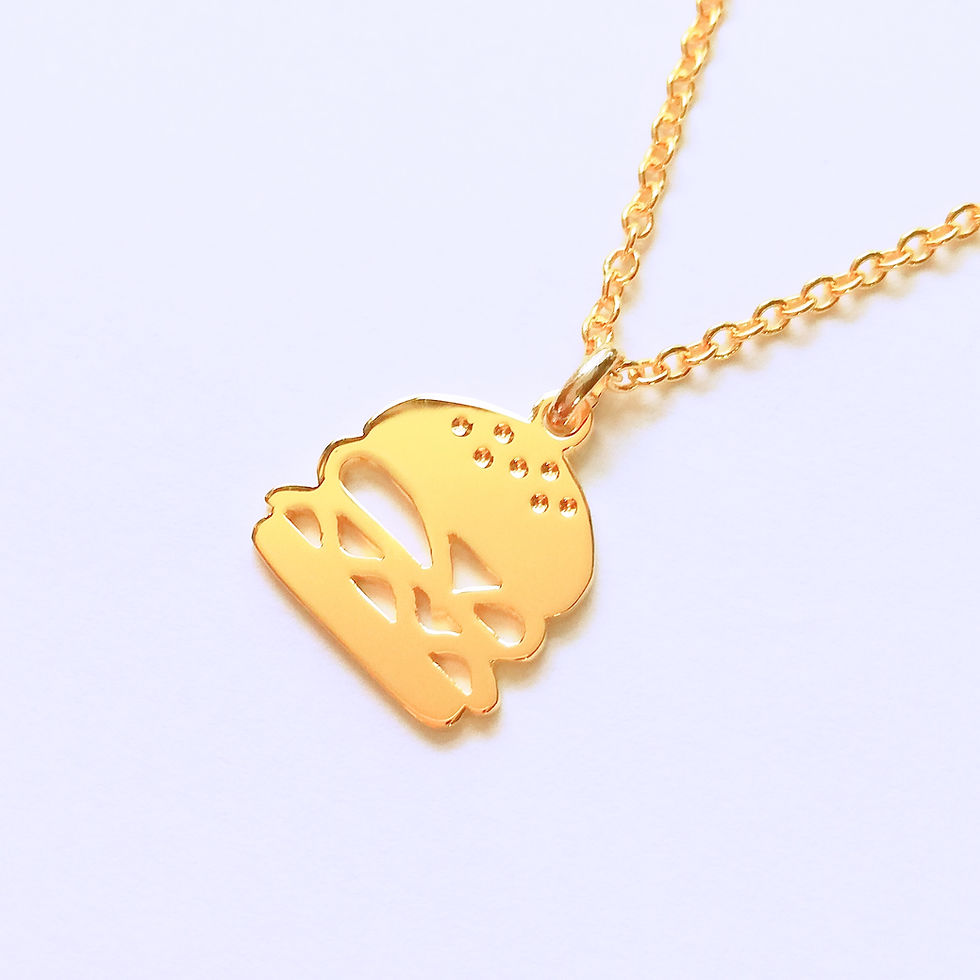 Gold hamburger necklace. The top is cutout and shiny, hanging from chain.