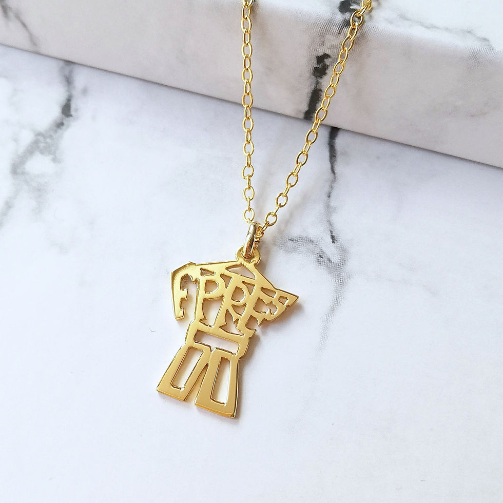 Thumbnail: Gold machinetta necklace on marble. The pendant top is flat and cutout, the handle is on the left side.