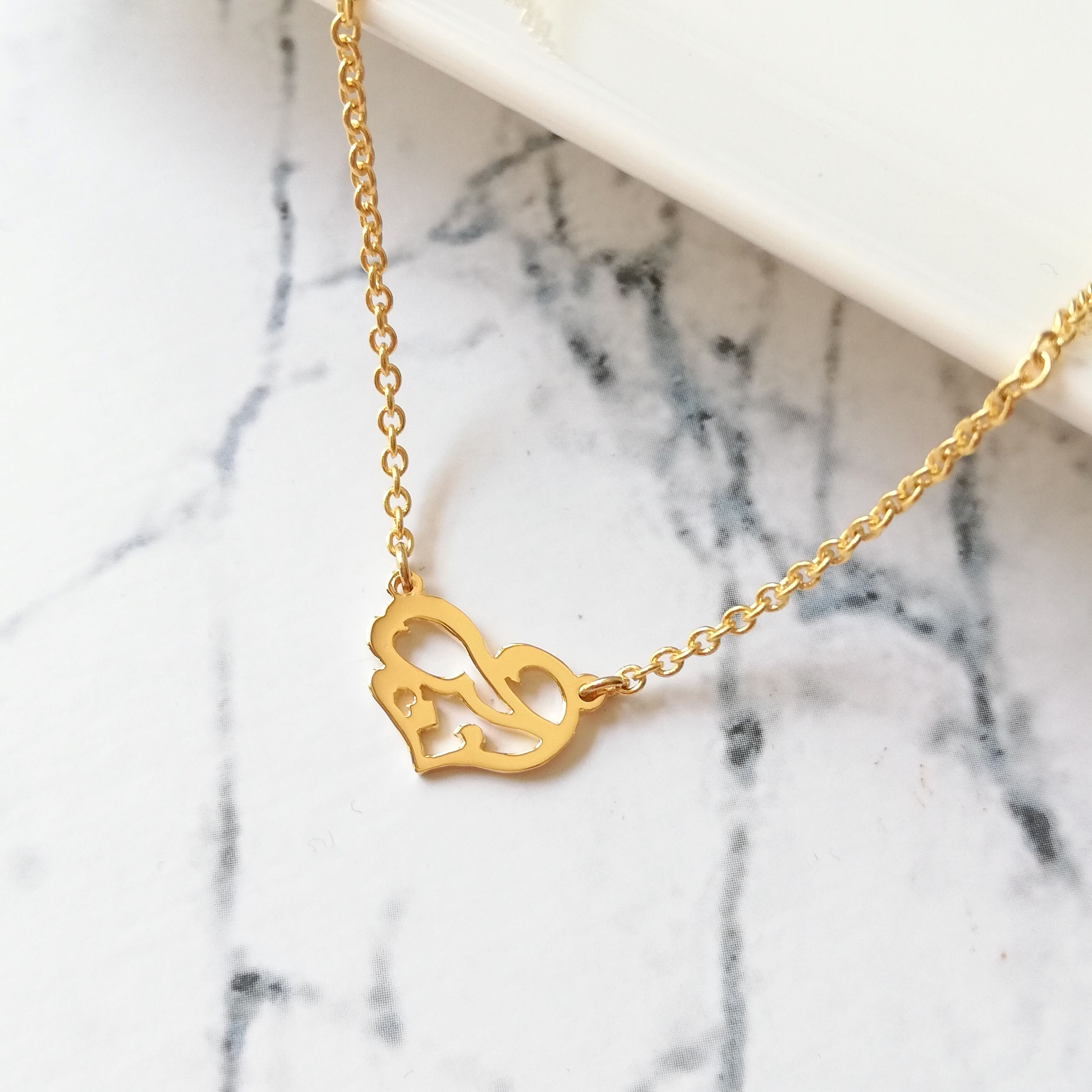 Gold landscaped heart necklace. The hear shape is embedded with Arabic word that means love.