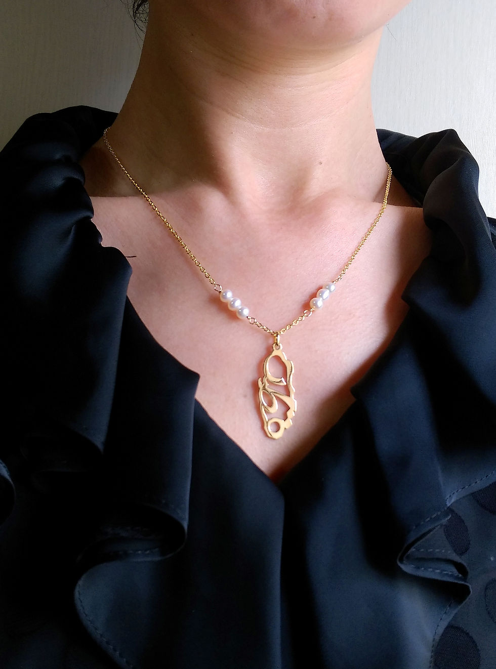 Thumbnail: A model is wearing Gold Qatar map pendant on black tops.