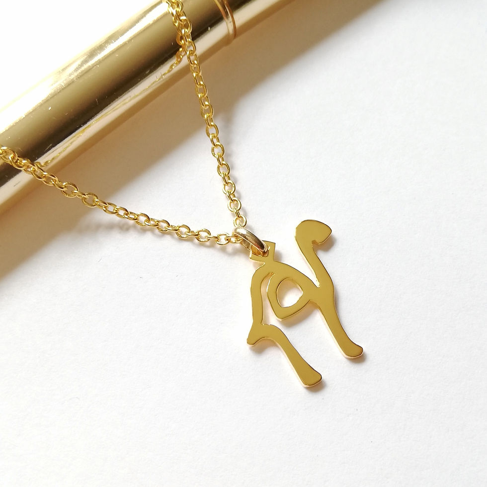 サムネイル： Gold camel necklace designed with Arabic word laying on white board.