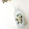 A painted glass bottle lying on its side with one vellum sticker applied and another sticker next to it, ready to be placed.