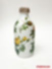 Finished decoupage glass bottle with vellum stickers and lace trim, ready to be used as a vase