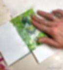 Using fingers to rub away the moistened paper, revealing the transferred image beneath.