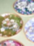 Colorful handmade clay ring dishes decorated with floral decoupage paper and metallic rims, styled with vintage-style jewelry.