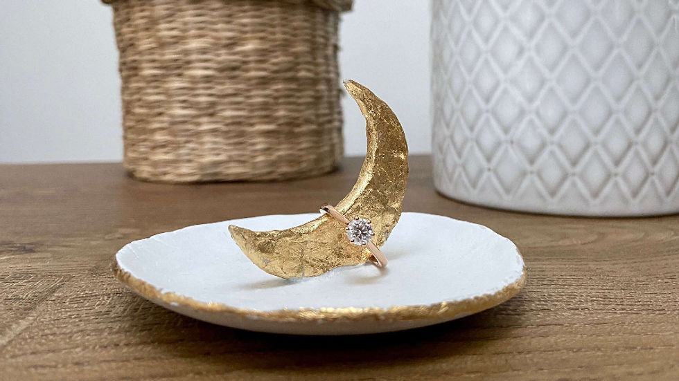 Handmade white clay dish with a raised gold moon holding a diamond ring.