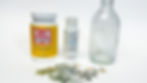 Supplies for a DIY decoupage bottle craft, including Mod Podge, enamel paint, a glass bottle, and vellum stickers on a white background