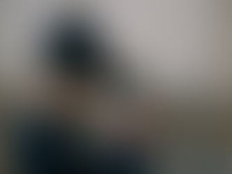 Girl sitting in front of a wall, face-down on her arms and resting on her knees