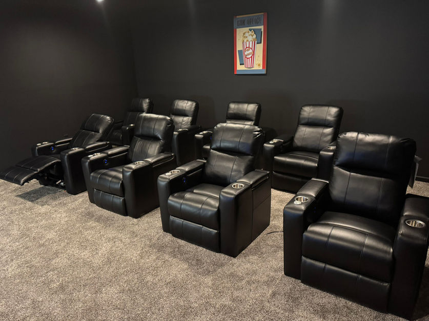 Eight electric reclining theater room chairs are shown with wall art.