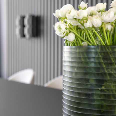 Close-up van een glazen vaas met bloemen op de eettafel in Woonhuis Castricum, subtiel stylingdetail door NINETY EIGHT Interior Design.