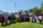 Group of people posing in front of a fire truck. An American flag and Liberian flag waves above. The mood is festive and bright.