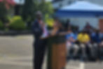 Zeogar Wilson, Chairman of the Board at the Antoinette Tubman Cheshire Home in Liberia speaks at a podium wearing a tricolor scarf.