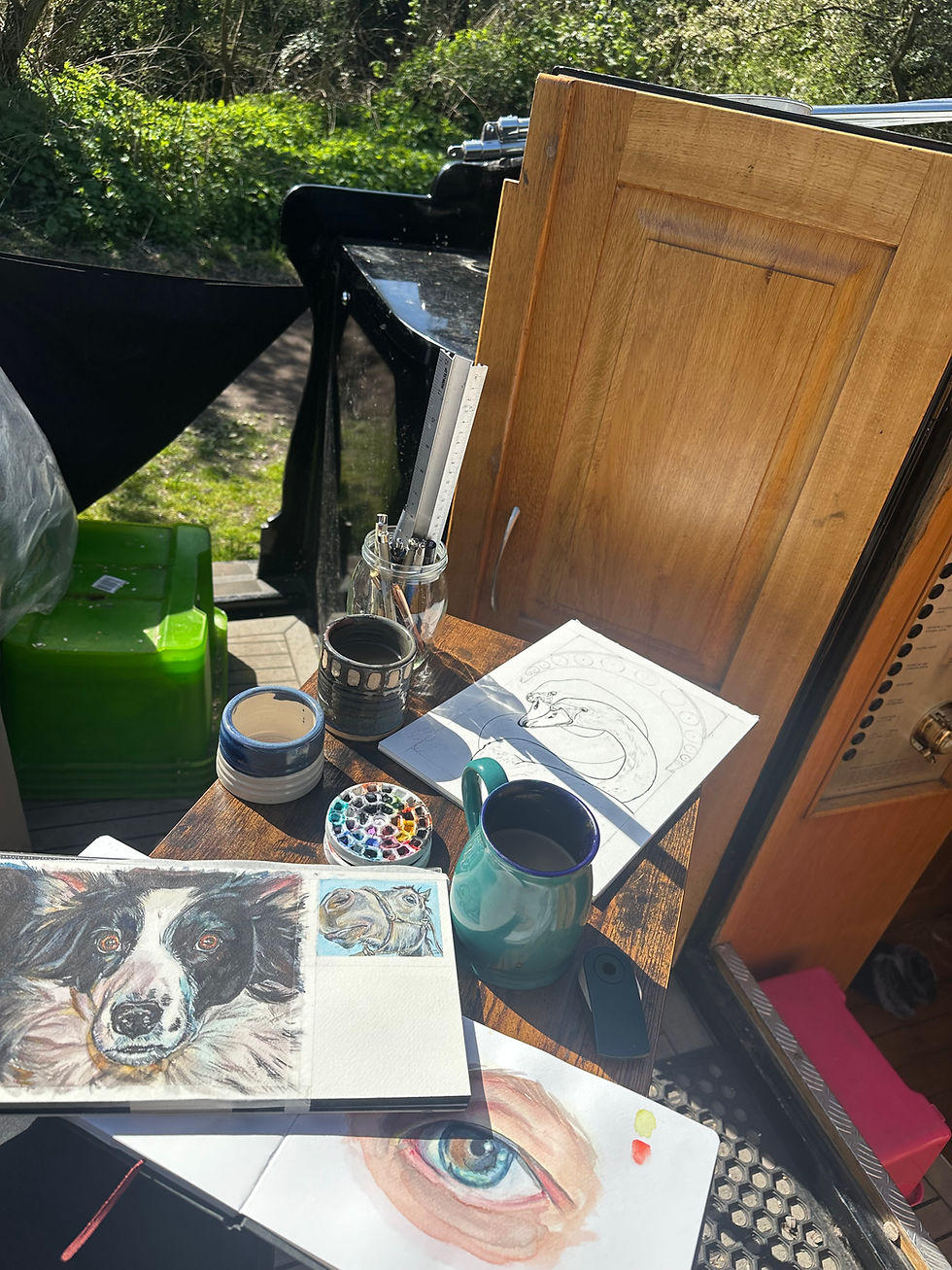 A picture showing a table covered in pieces of partly finished artwork, paints, brushes, and a cup of coffee, on the back of a boat.
